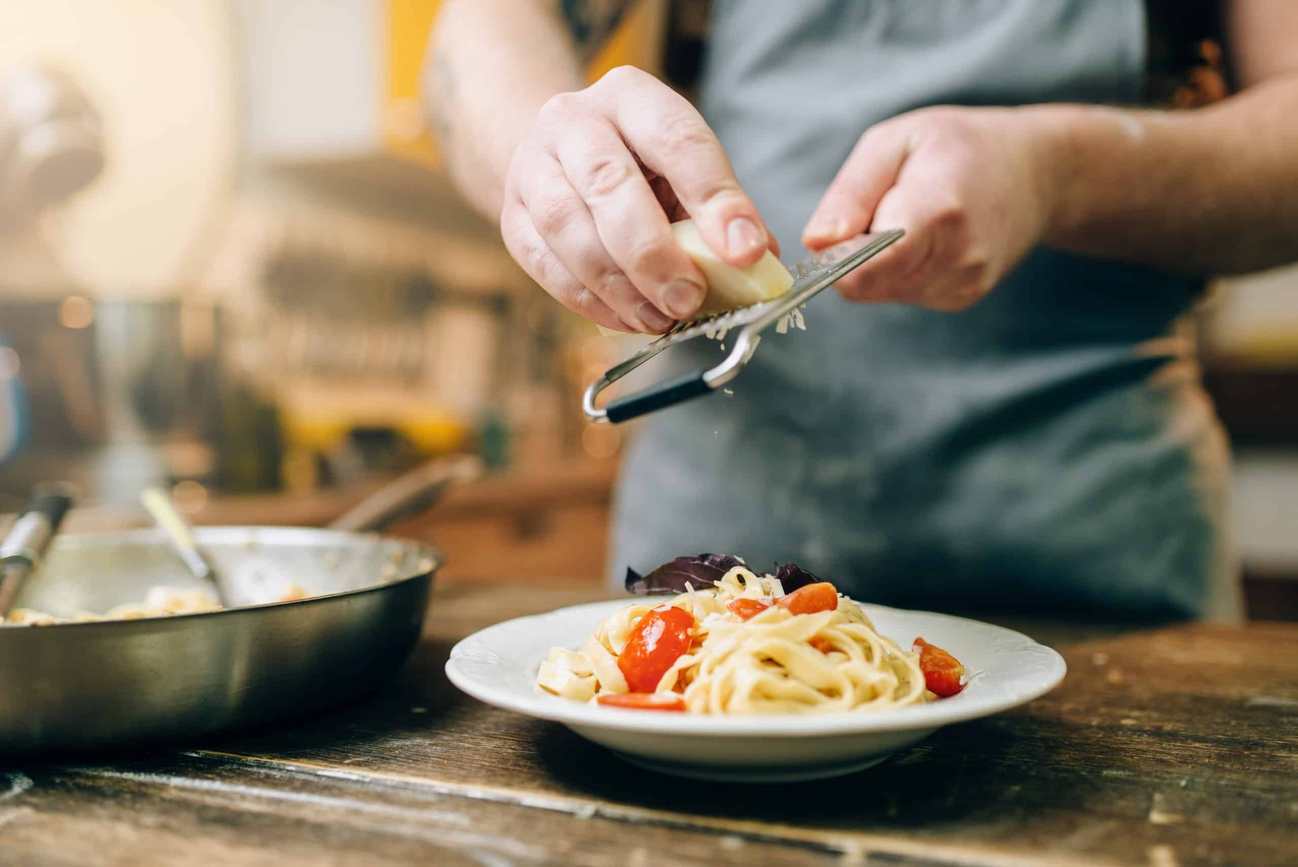 Chef grates cheese to the plate with fresh pasta Chef grates cheese to the plate with fresh pasta