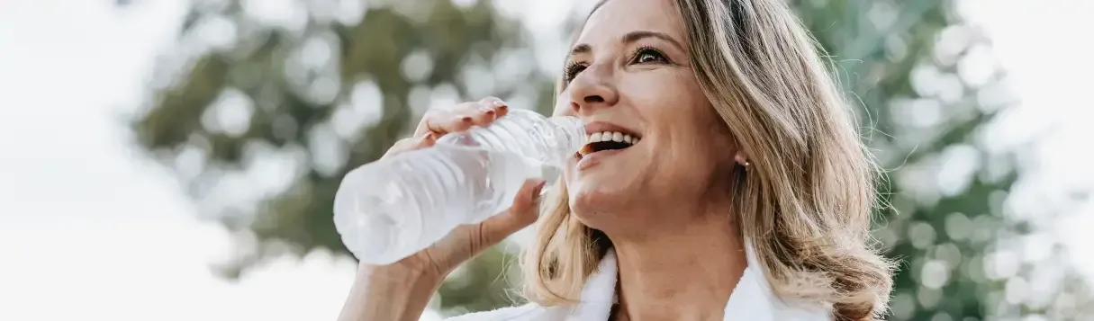 iStock-1945475261 3 (1) woman drinking from a water bottle after a workout outside